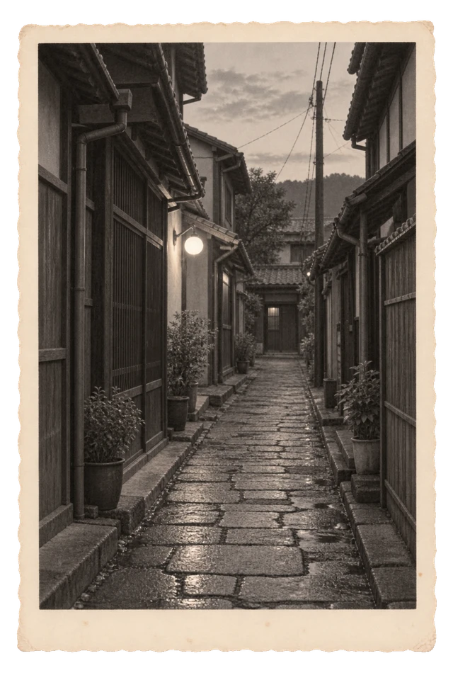 雨に濡れた石畳と小さな灯りが続く、誰もいない町の路地。